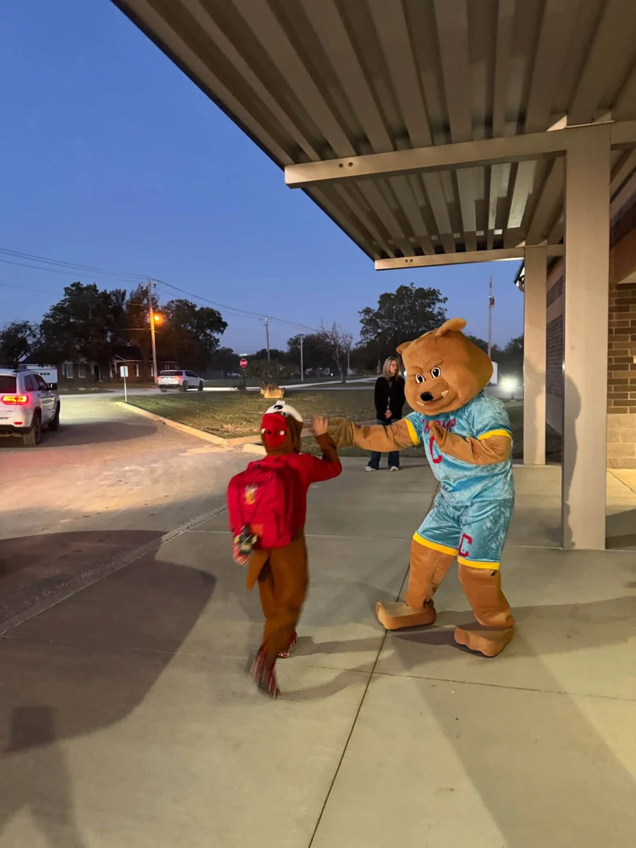 CHOMP mascot greeting a costumed student outside Bryson Elementary