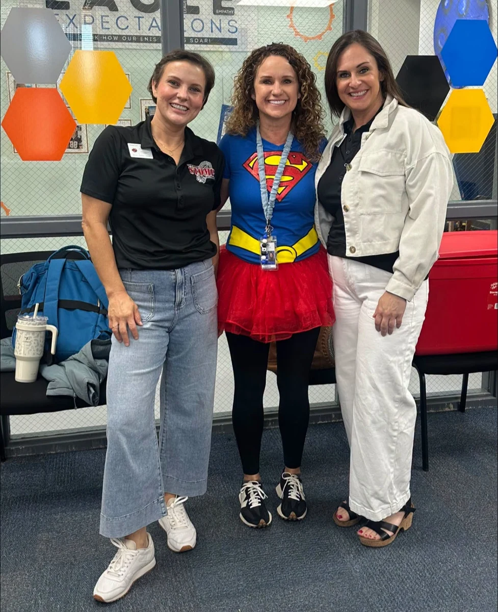 Three adults posing together at the school program